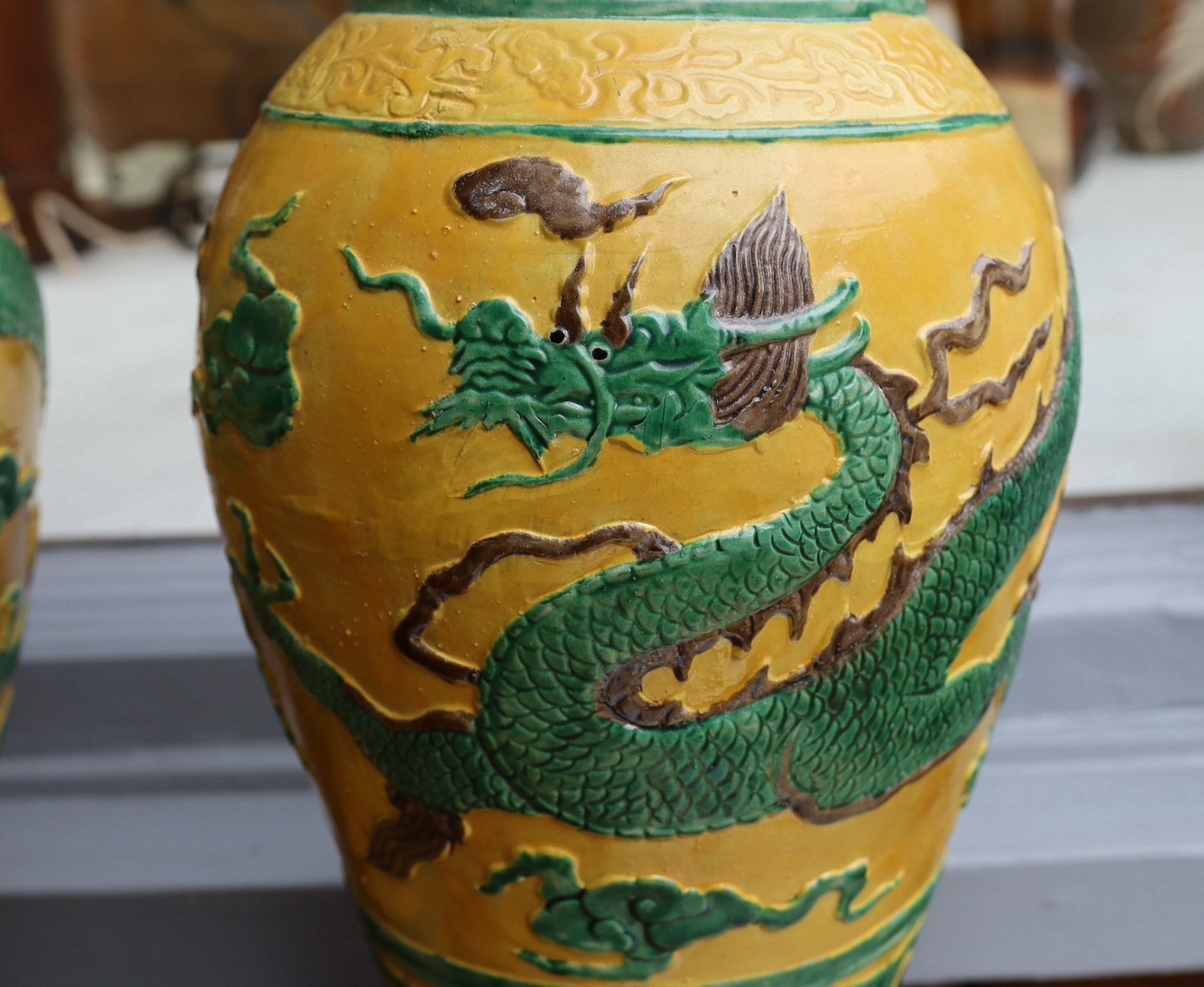 A pair of Chinese yellow glazed baluster vases decorated with bands of flowers and dragons, on hardwood stands, height 67cm. height overall 85cm